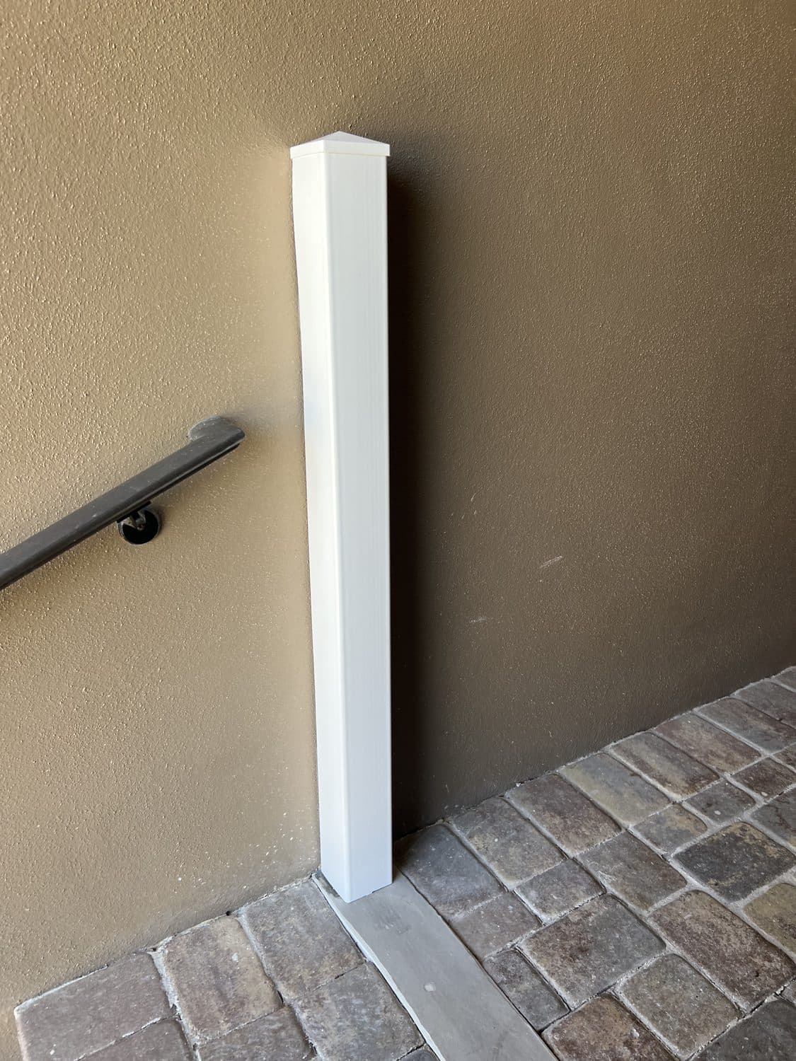 White capped post cover sleeved over a mounted HydroDam flood barrier post beside a residential entry