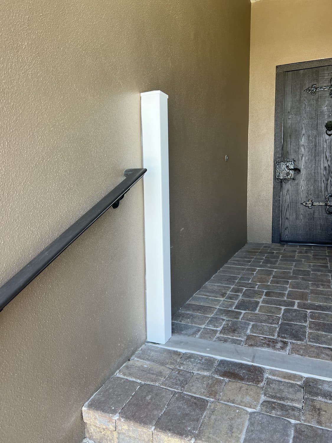 Covered HydroDam barrier post reading as architectural trim at a paver entryway and front door